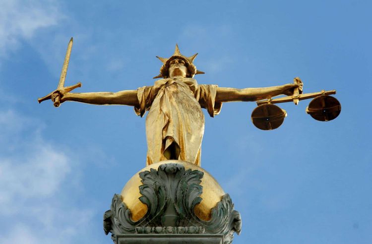 View of the gold statue of the figure of justice, holding scales and a sword, on top of the Central Criminal Court, also referred to as Old Bailey, in central London.